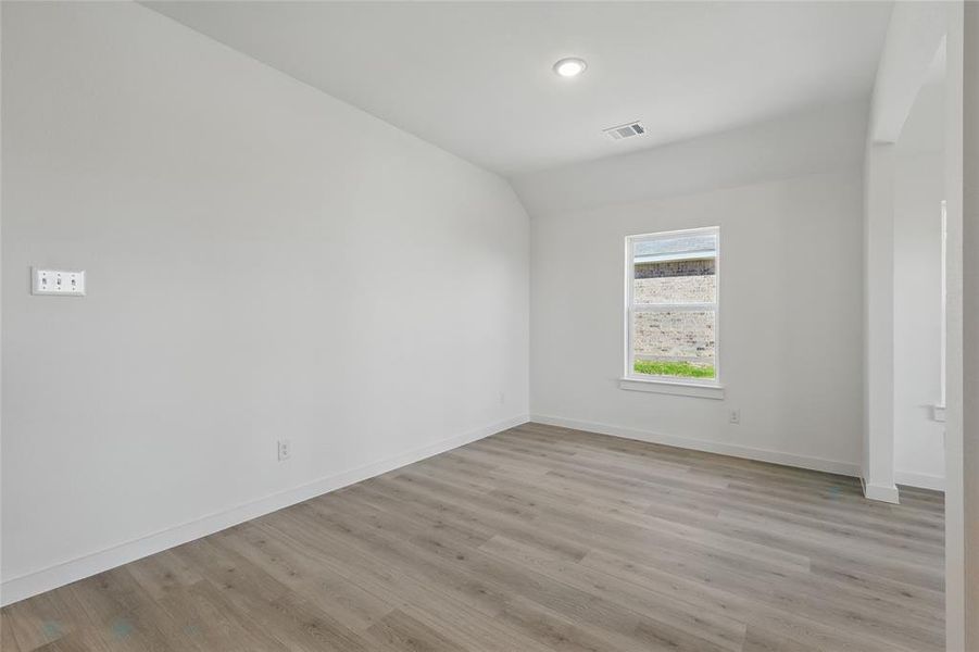 Spare room with visible vents, baseboards, vaulted ceiling, and light wood-style flooring Spare room with visible vents, baseboards, vaulted ceiling, and light wood-style flooring