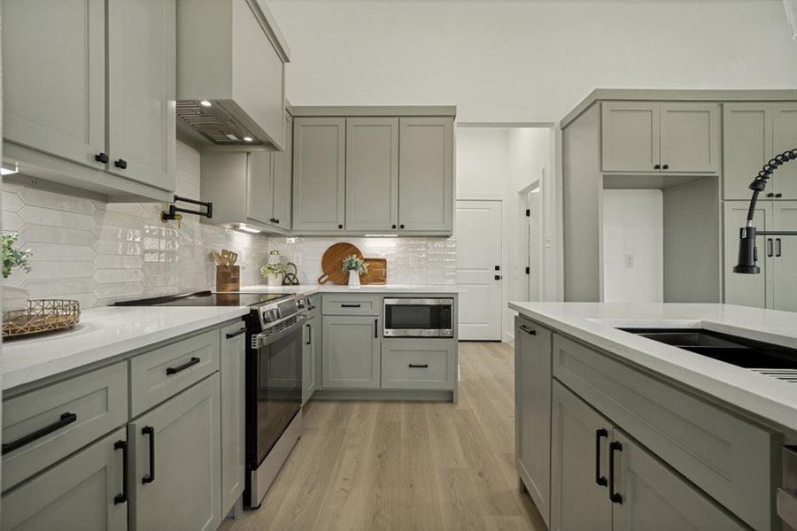 Kitchen featuring light gray cabinetry, white countertops, stainless steel appliances, and wood-finish flooring Kitchen featuring light gray cabinetry, white countertops, stainless steel appliances, and wood-finish flooring