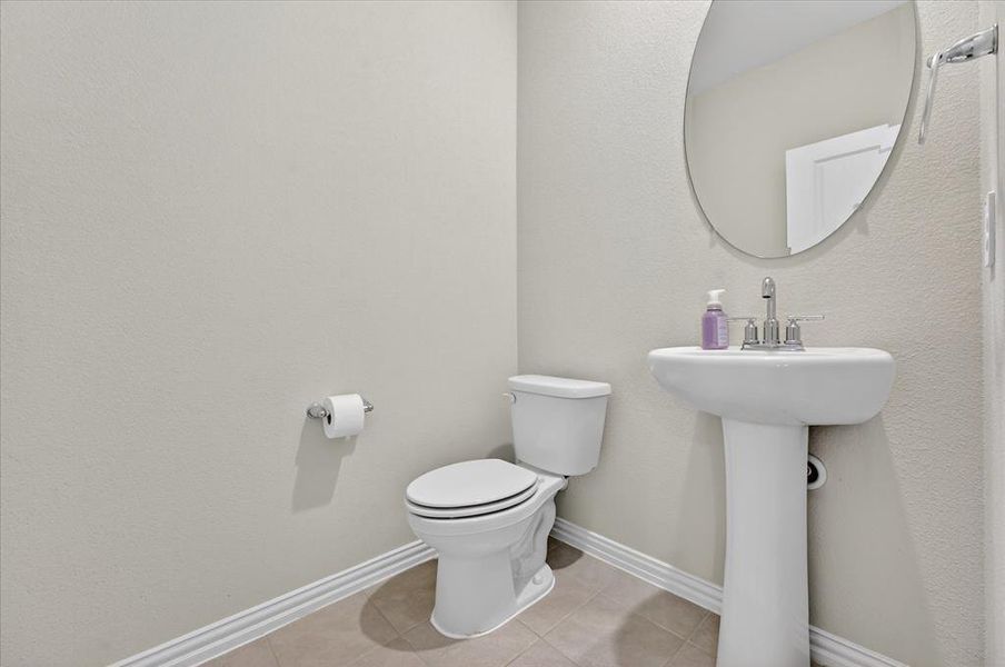 Half bathroom with toilet and light tile patterned flooring