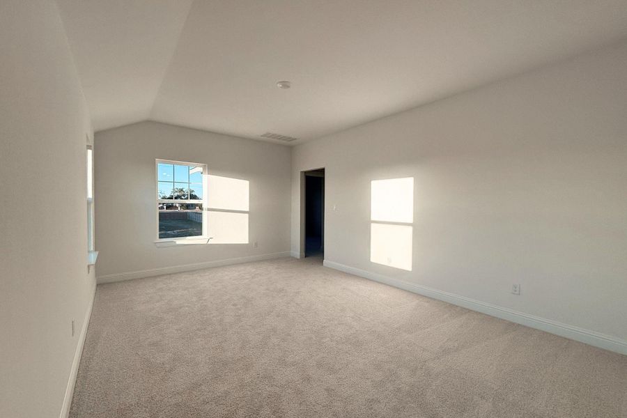 Unfurnished room featuring light colored carpet and vaulted ceiling