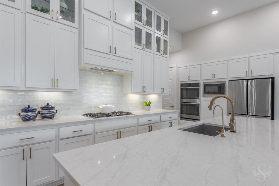 The impressive quartz island offers abundant workspace and includes a large undermount sink with designer fixtures. Towering cabinetry, glass-front displays and a statement backsplash give this kitchen incredible style. The impressive quartz island offers abundant workspace and includes a large undermount sink with designer fixtures. Towering cabinetry, glass-front displays and a statement backsplash give this kitchen incredible style.