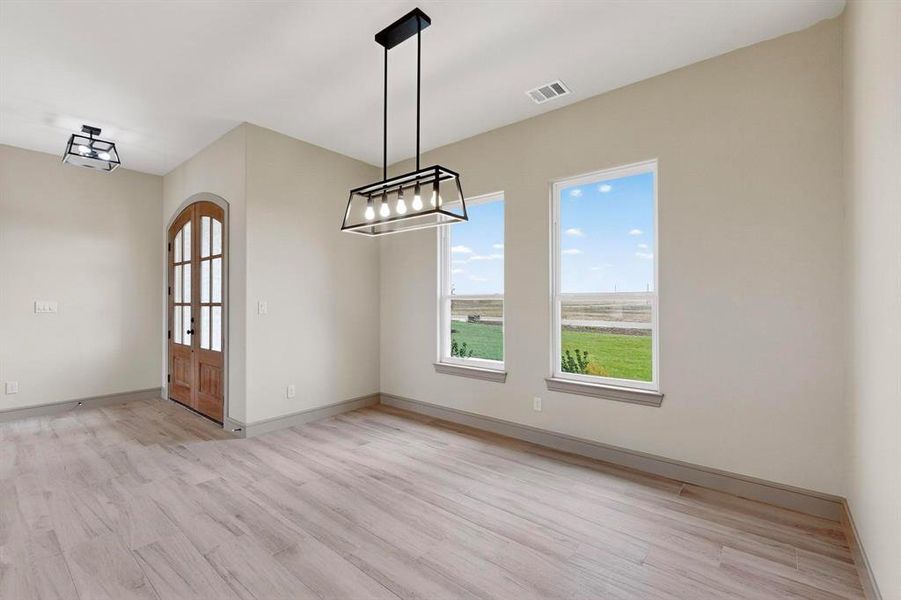 Unfurnished dining area featuring light wood finished floors and arched walkways Unfurnished dining area featuring light wood finished floors and arched walkways