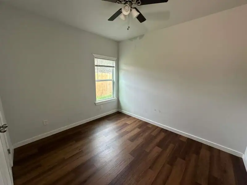 Empty room with dark wood-type flooring and ceiling fan