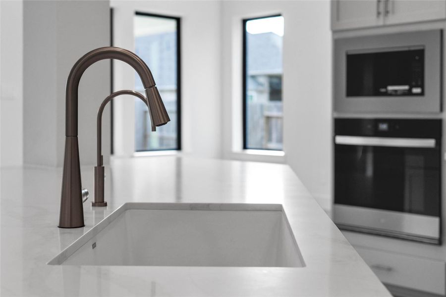 The kitchen is anchored by a Moen Stainless Steel Sleek kitchen faucet, paired with a matching secondary beverage for a coordinated and highly functional workspace. The kitchen is anchored by a Moen Stainless Steel Sleek kitchen faucet, paired with a matching secondary beverage for a coordinated and highly functional workspace.