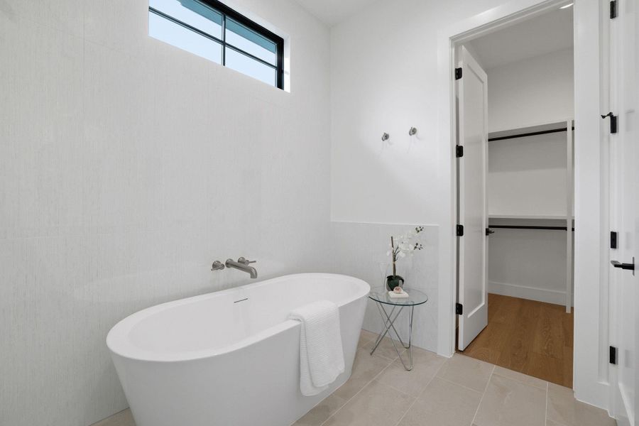 Bathroom featuring tile patterned floors, a freestanding tub, and a walk in closet