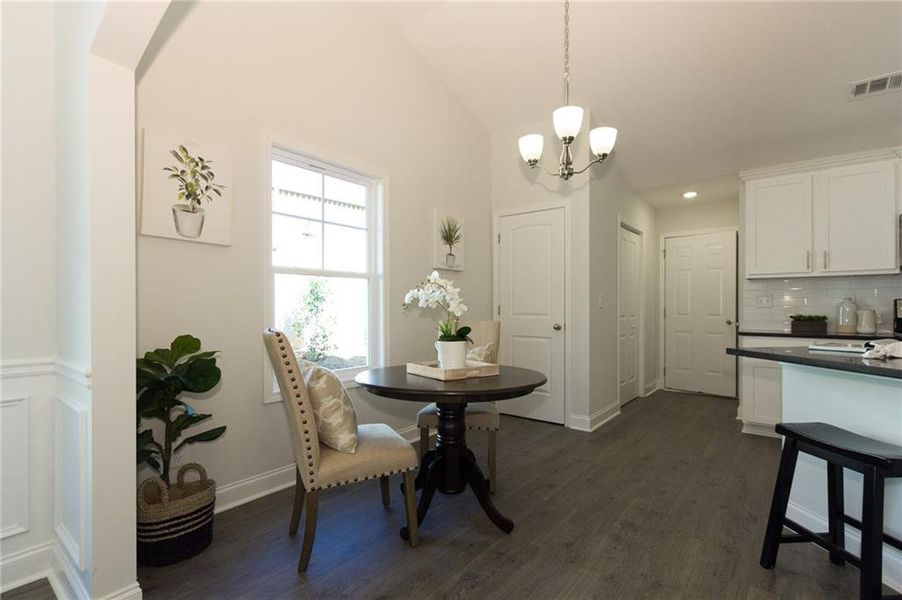 Dining space featuring dark hardwood / wood-style flooring, lofted ceiling, and a chandelier