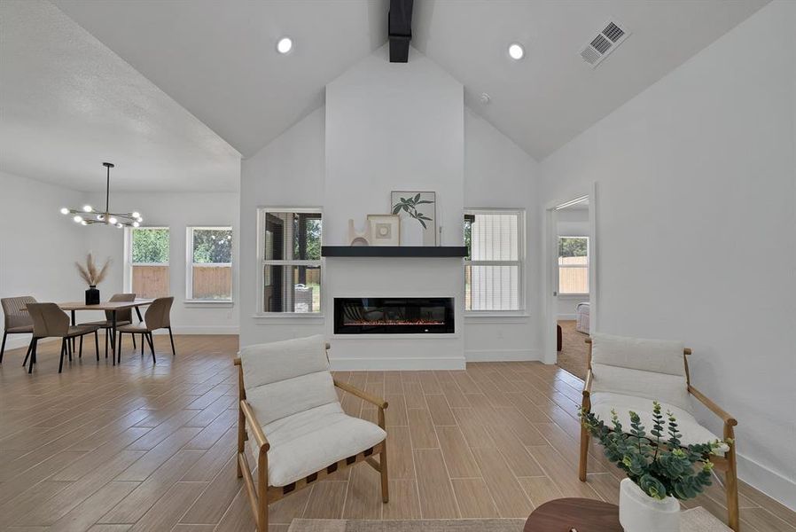 Living area with beamed ceiling, tiled floors, high vaulted ceiling, a glass covered fireplace, and a chandelier