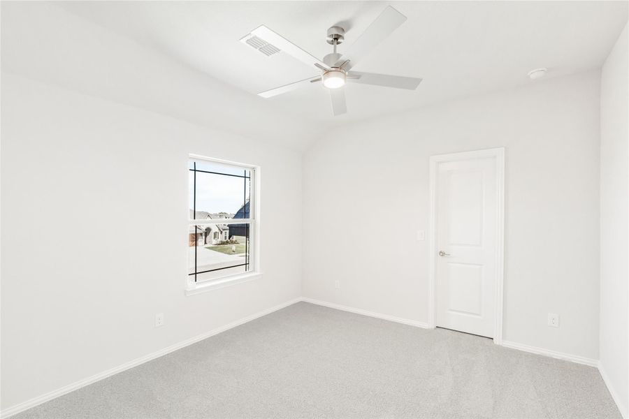 Empty bedroom with white walls, carpet flooring, ceiling fan, and a single window with neighborhood view Empty bedroom with white walls, carpet flooring, ceiling fan, and a single window with neighborhood view