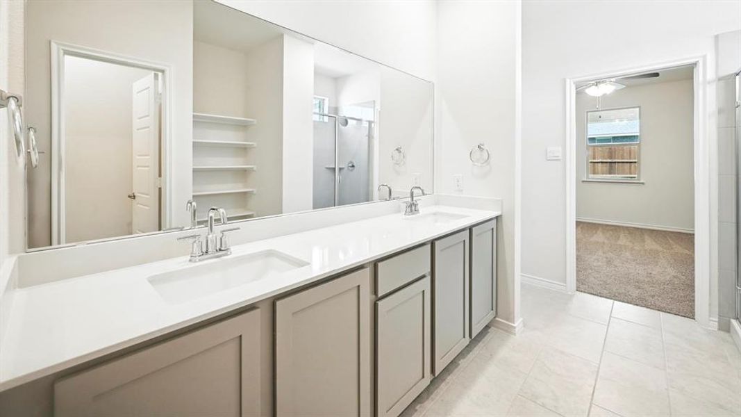 Bathroom featuring a shower stall, double vanity, light tile patterned floors, and light carpet