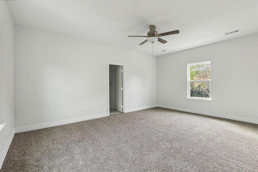 Carpeted empty room featuring ceiling fan