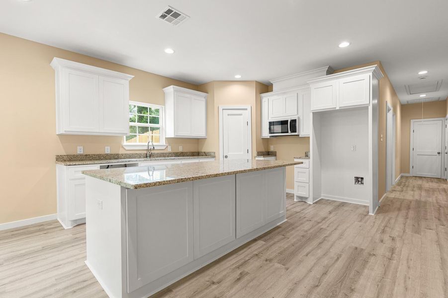 Kitchen featuring a center island, white cabinets, light wood-type flooring, recessed lighting, and light stone countertops