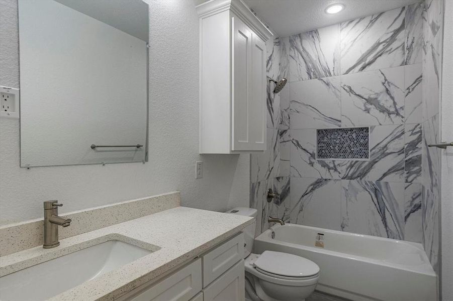 Full bathroom featuring tiled shower / bath, toilet, and large vanity