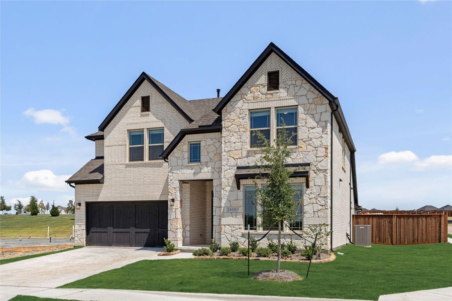 Two-story home with stone and brick exterior, two-car garage, and manicured front lawn
