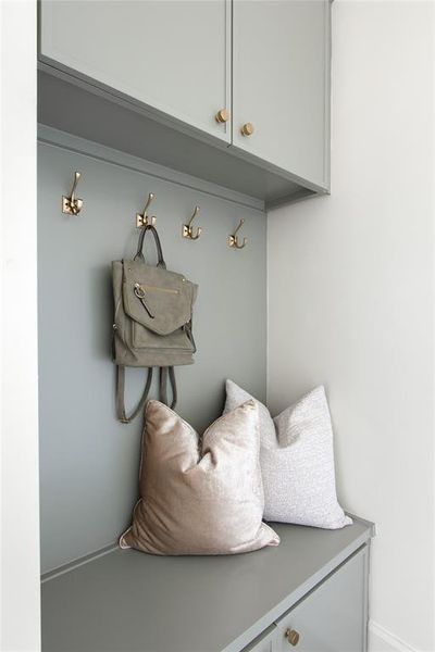 Built-in storage bench with lower cabinetry, overhead wall cabinets, and brass hardware