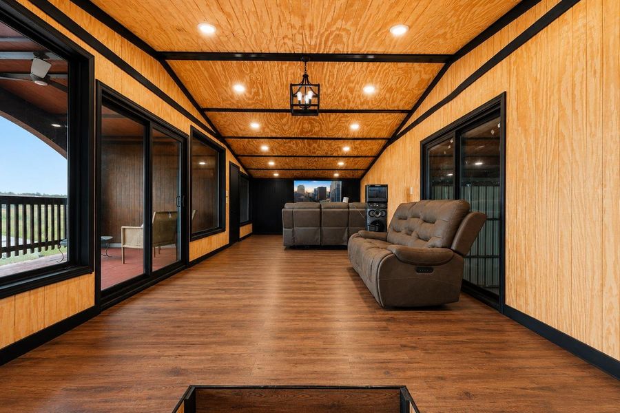 Hardwood floors and bright recessed lighting adorn this spacious entertainment room.