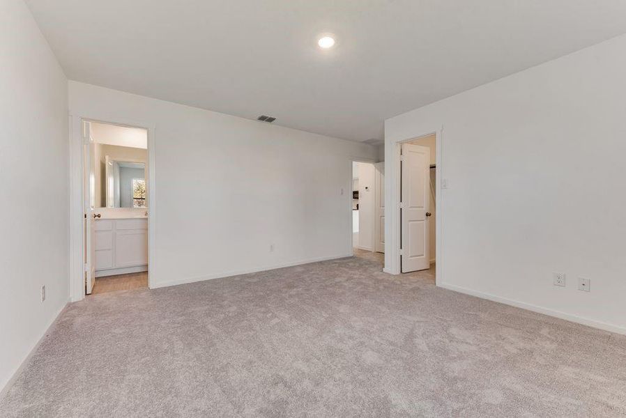 Unfurnished bedroom with light colored carpet, ensuite bath, visible vents, and baseboards