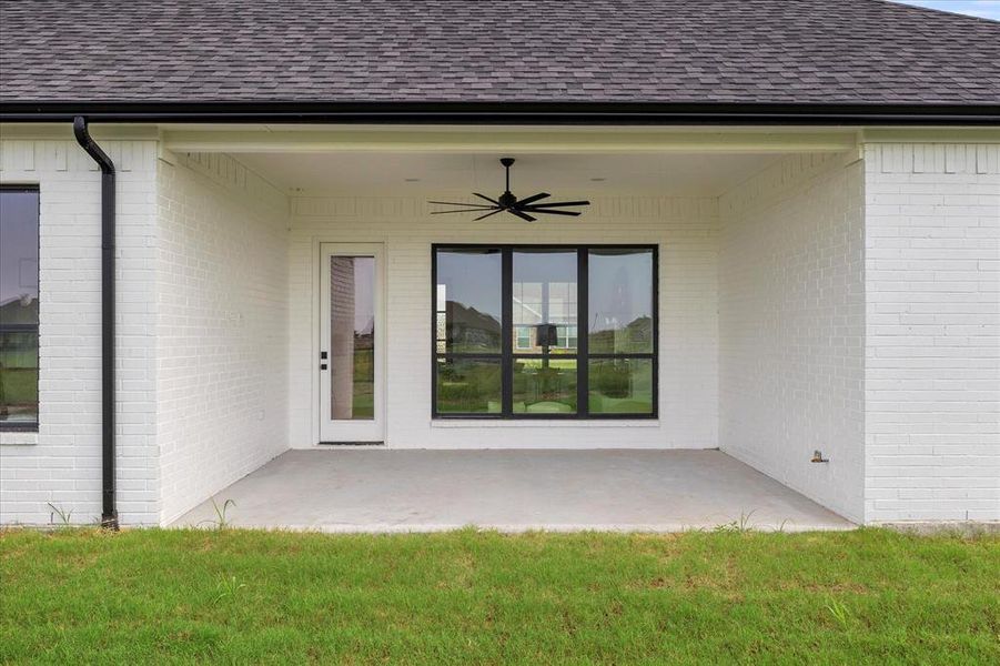 Doorway to property featuring a patio, a yard, and ceiling fan