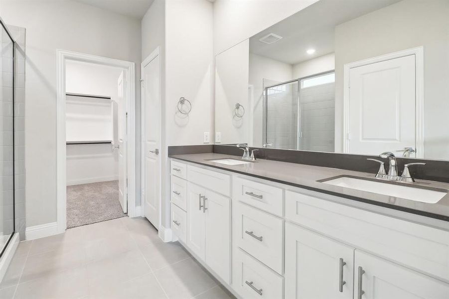 Bathroom with tile patterned flooring, vanity, and a shower with door