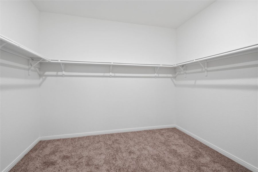 The spacious primary bedroom walk-in closet offers shelving, hanging rods, and ample storage space to keep your wardrobe organized.