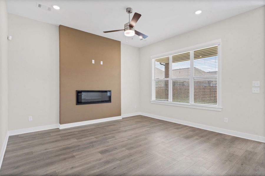 Recessed lighting, wood-finish flooring, ceiling fan, large window with blinds, and a built-in electric fireplace
