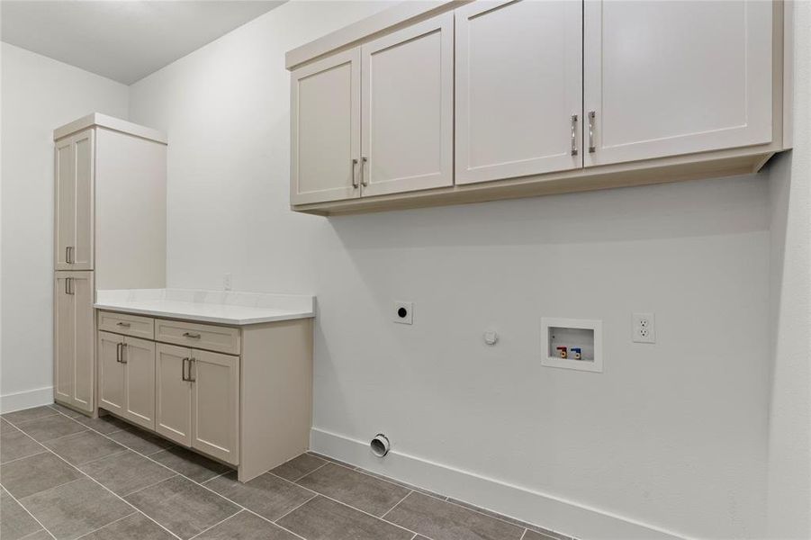 Laundry area featuring hookup for a gas dryer, hookup for an electric dryer, cabinet space, tile patterned flooring, and hookup for a washing machine Laundry area featuring hookup for a gas dryer, hookup for an electric dryer, cabinet space, tile patterned flooring, and hookup for a washing machine
