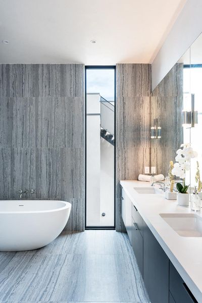 A freestanding soaking tub complements the double vanity in this sleek, modern primary bathroom. A freestanding soaking tub complements the double vanity in this sleek, modern primary bathroom.