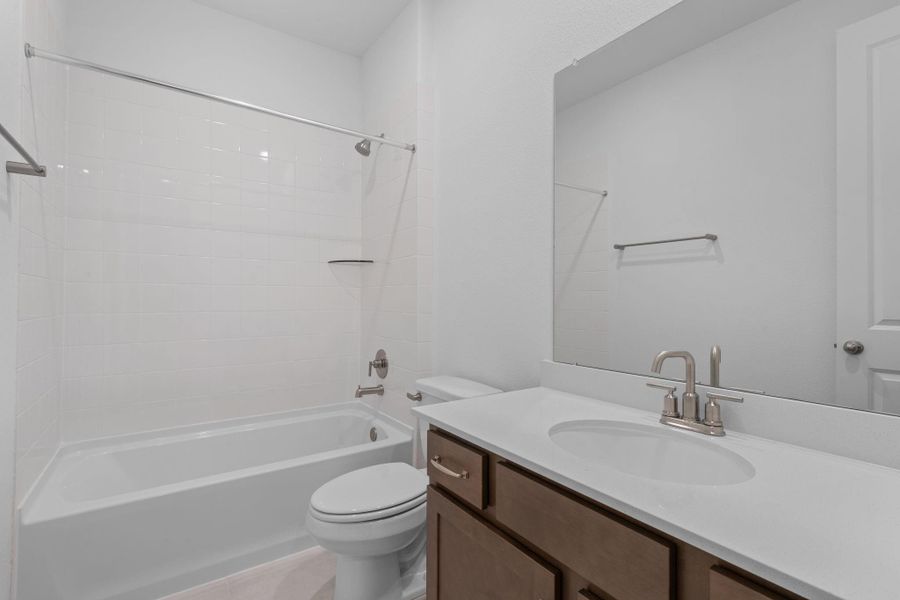 The secondary bath features tile flooring, white cabinetry and light countertops and a shower/tub combo. Perfect for accommodating any visiting family and friends.