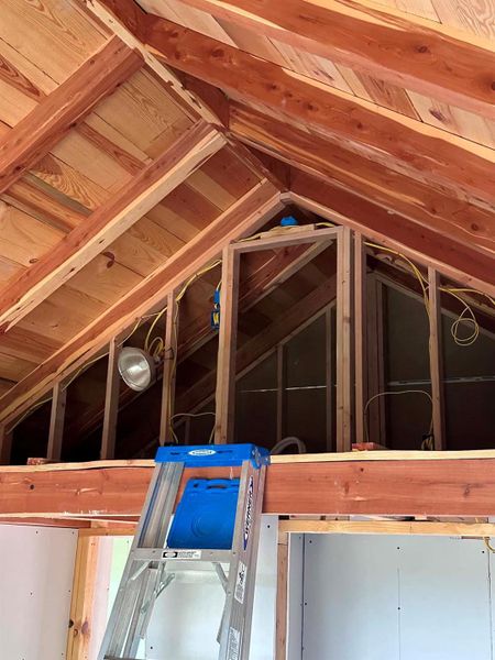 Exposed wood beams add architectural character to this unfinished attic space, promising future potential.