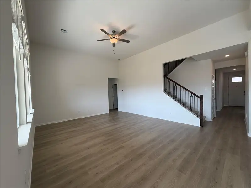 Unfurnished living room with wood finished floors, stairs, and ceiling fan
