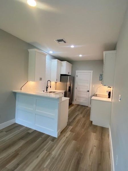 A streamlined culinary space features modern white cabinetry and resilient wood-look flooring. A streamlined culinary space features modern white cabinetry and resilient wood-look flooring.