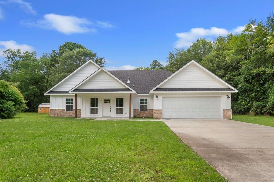 This charming single-story home features a modern exterior with a spacious front lawn, a two-car garage, and a welcoming front porch. The property is surrounded by lush greenery, offering a serene, private setting. This charming single-story home features a modern exterior with a spacious front lawn, a two-car garage, and a welcoming front porch. The property is surrounded by lush greenery, offering a serene, private setting.