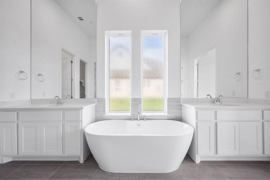 Bathroom featuring vanity, a wealth of natural light, and a soaker tub