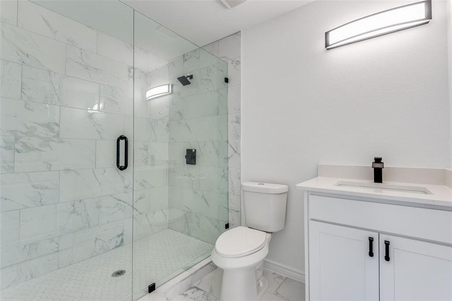 Bathroom featuring vanity, toilet, and a shower with shower door