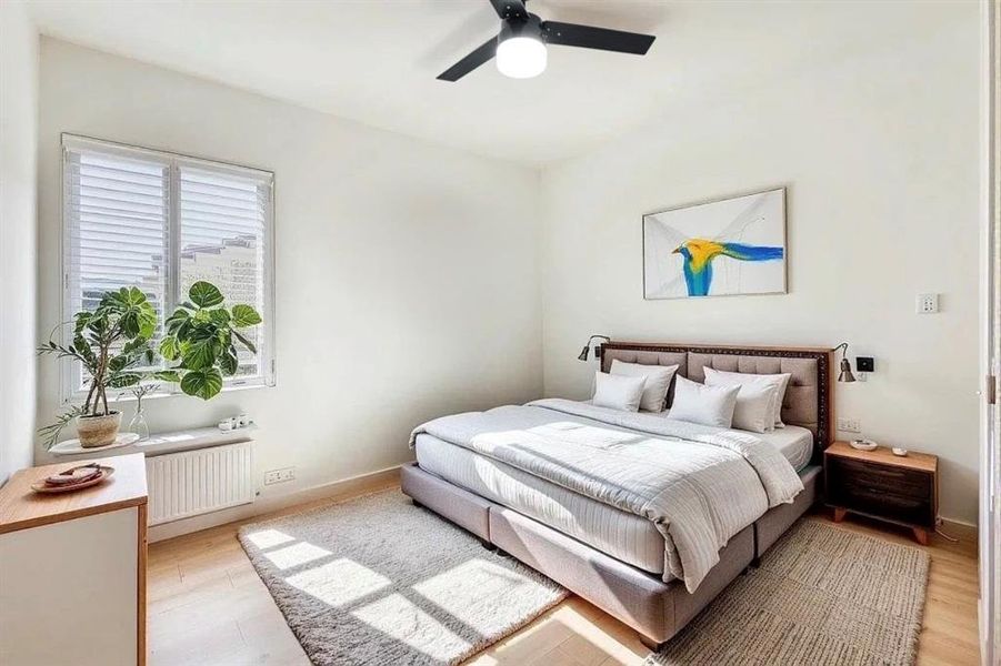 Bedroom with radiator, light wood-style floors, and a ceiling fan
