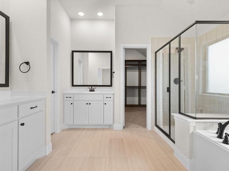 Bathroom with vanity, a stall shower, a walk in closet, a garden tub, and recessed lighting