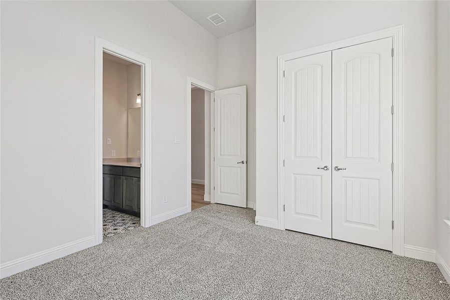 Unfurnished bedroom with light carpet, a closet, and connected bathroom