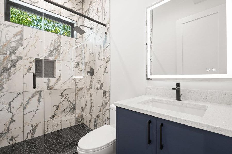 Bathroom with vanity and a marble finish shower