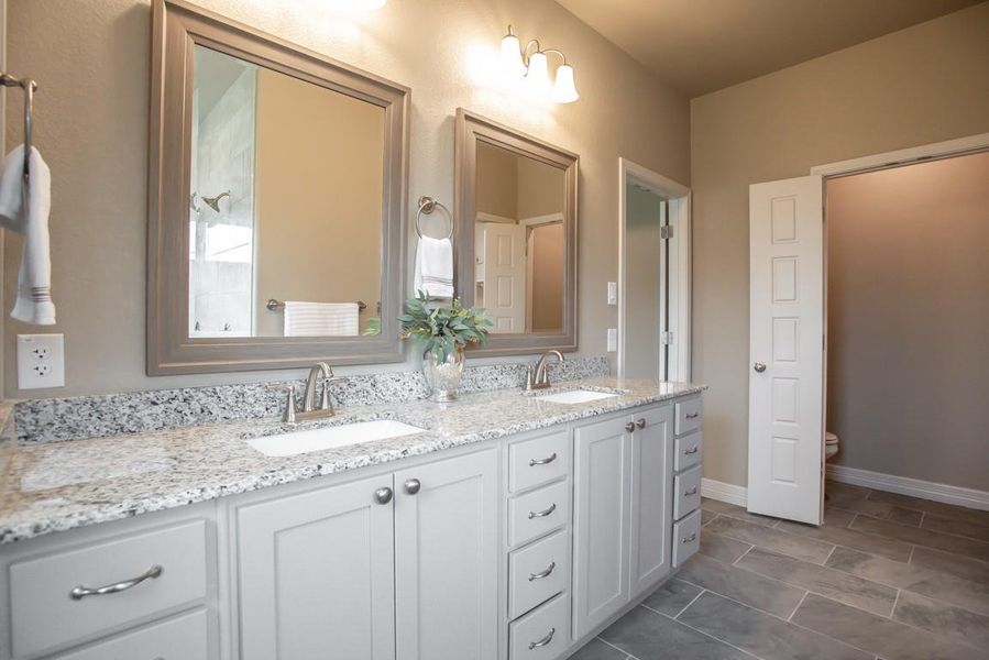 Full bath with double vanity, toilet, and a sink