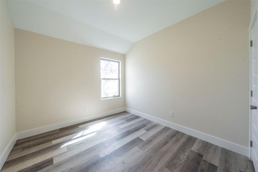 Spare room with lofted ceiling, baseboards, and wood finished floors