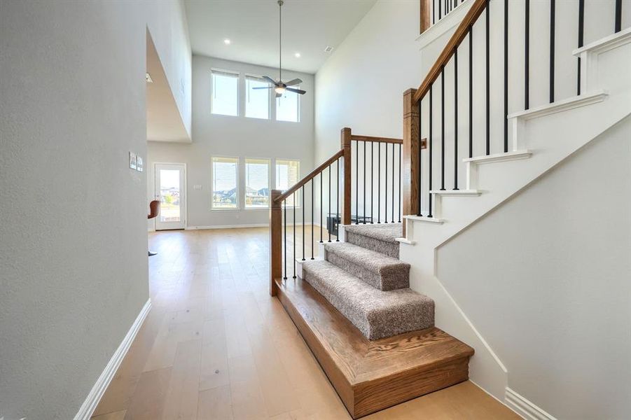 Stairs with wood finished floors, plenty of natural light, ceiling fan, a high ceiling, and recessed lighting Stairs with wood finished floors, plenty of natural light, ceiling fan, a high ceiling, and recessed lighting