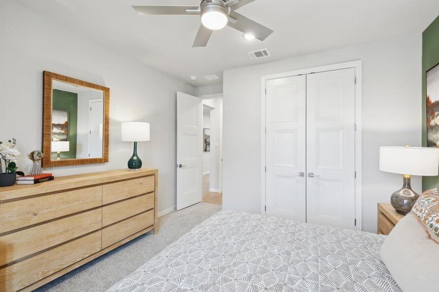 Bedroom with light colored carpet, a closet, and ceiling fan