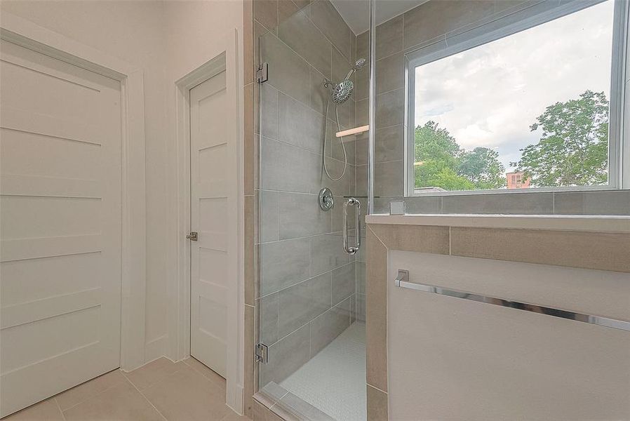 Oversized frameless shower with subway tile surround, built-in bench, and shower head with handheld sprayer and separate water closet complete the bathroom.