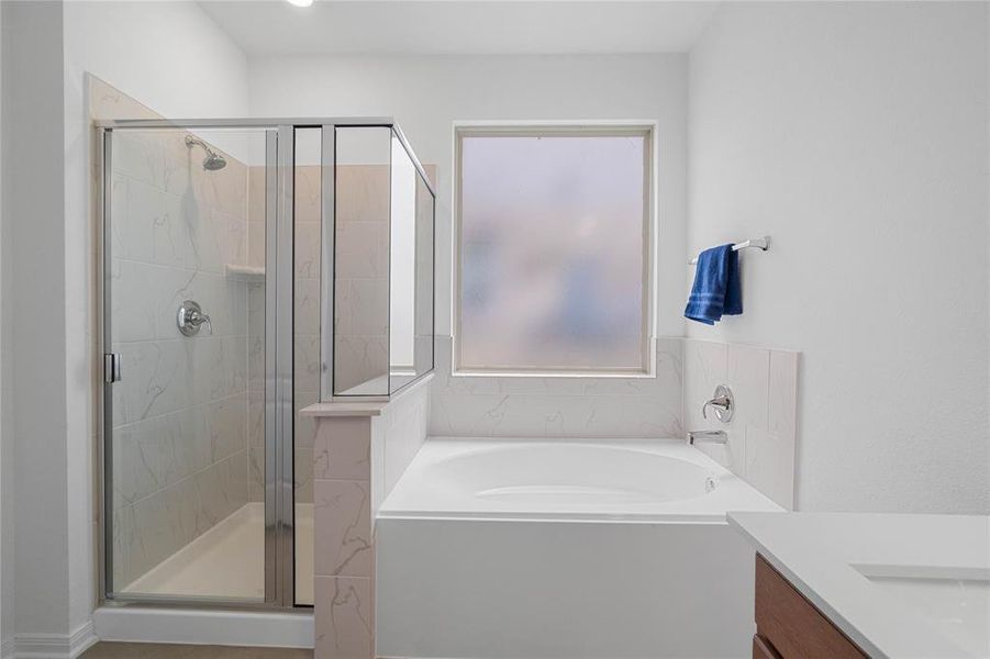 This primary bathroom is definitely move-in ready! Featuring an oversized framed walk-in shower with tile surround, separate garden tub for soaking after a long day with custom tile detailing, stained cabinets with light countertops, spacious walk-in closet with shelving, high ceilings, neutral paint, sleek and modern finishes.