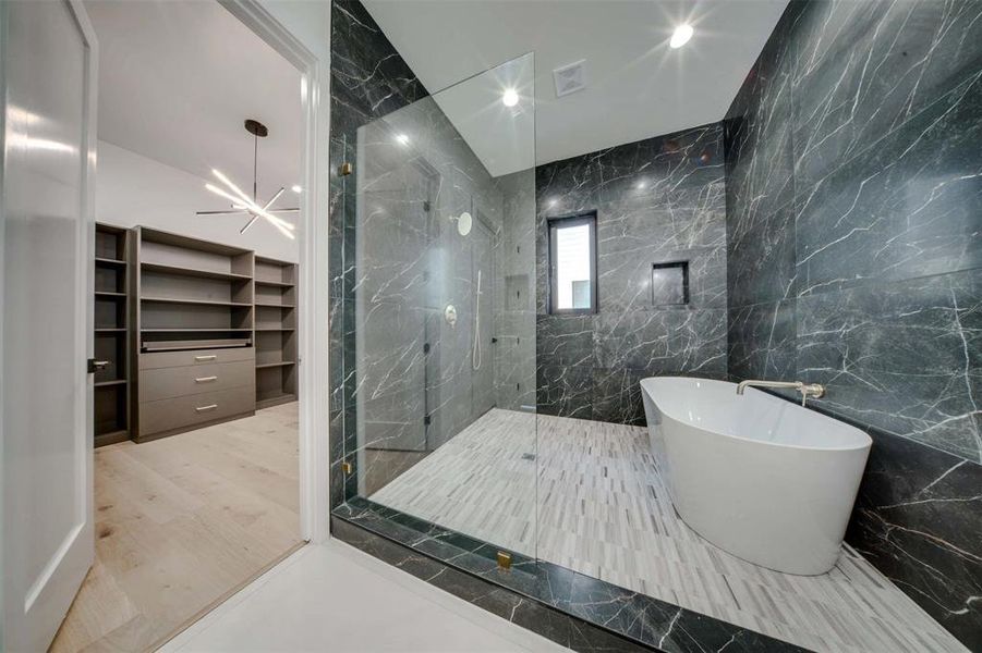 Bathroom with hardwood / wood-style floors, tile walls, independent shower and bath, and a notable chandelier