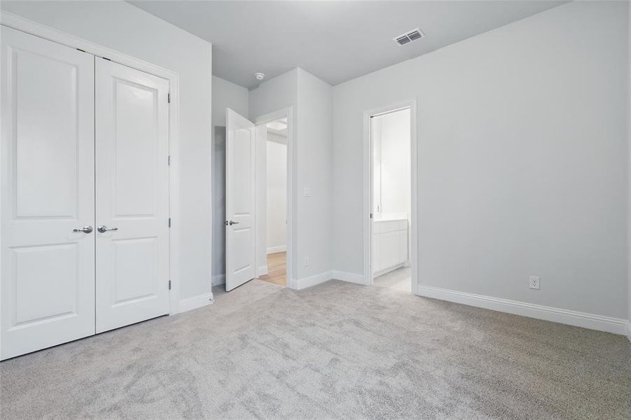 Unfurnished bedroom with carpet floors, baseboards, a closet, and connected bathroom Unfurnished bedroom with carpet floors, baseboards, a closet, and connected bathroom