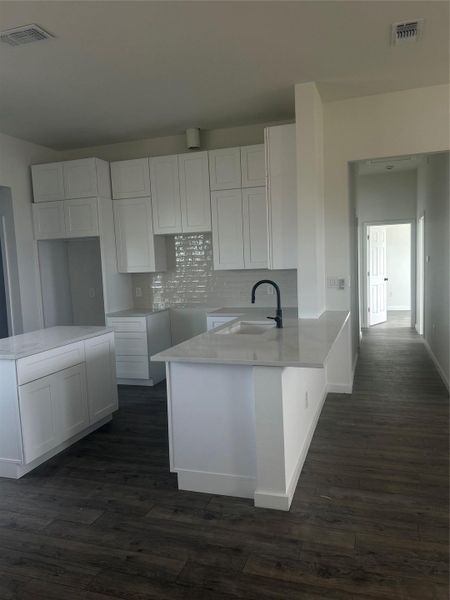 Kitchen featuring white cabinets, tasteful backsplash, and light stone countertops Kitchen featuring white cabinets, tasteful backsplash, and light stone countertops
