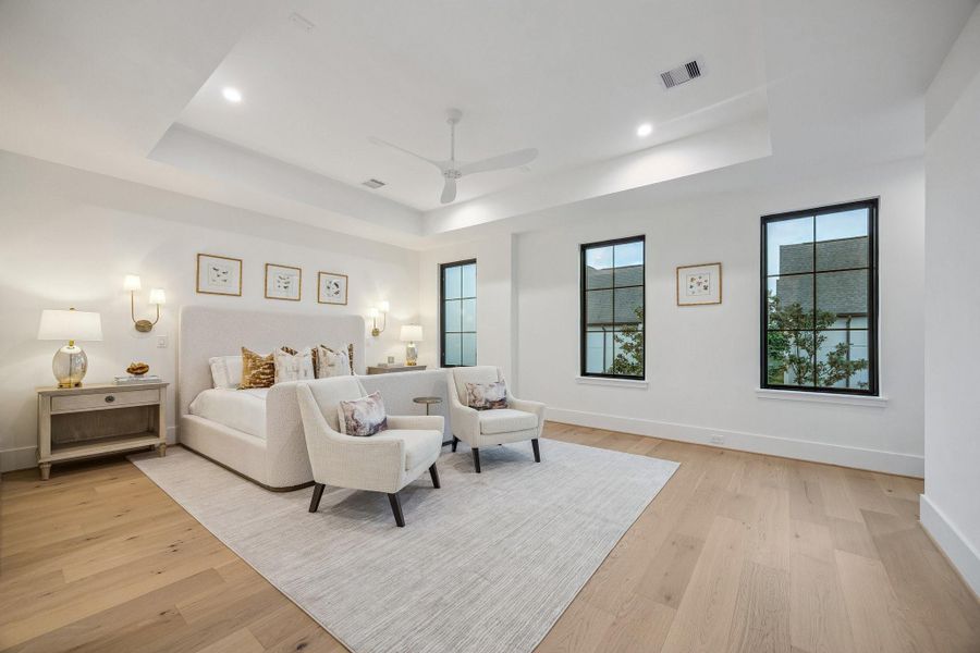 The serene bedroom is designed as a calm, light-filled retreat that blends modern simplicity with soft, inviting warmth. Architectural details such as the coffered ceiling and modern ceiling fan add dimension and functionality without overwhelming the space. Clean lines, reading lights, and warm woods, complete this beautiful room.  There is also a coffee bar, not shown in the photo.