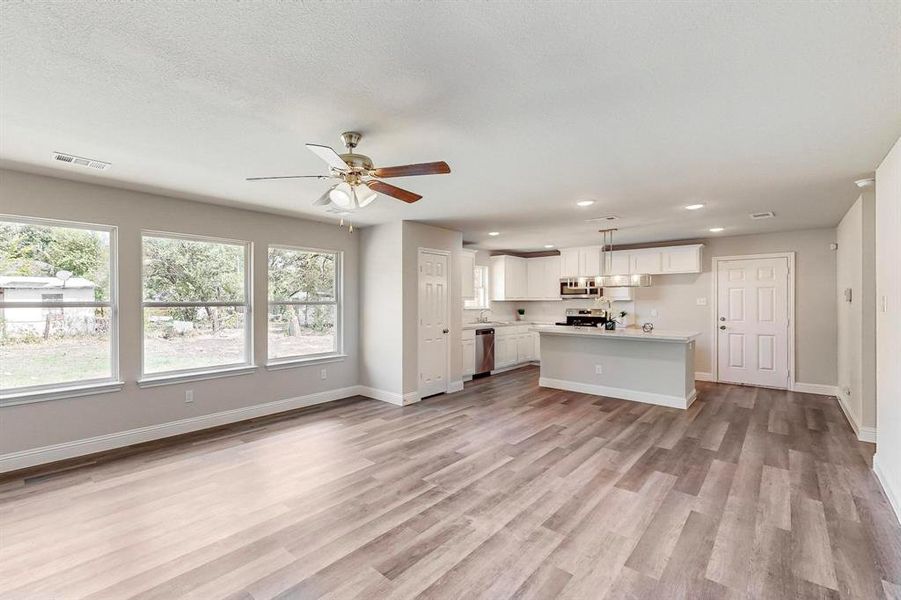 Unfurnished living room featuring light hardwood / wood-style flooring, ceiling fan, and a healthy amount of sunlight