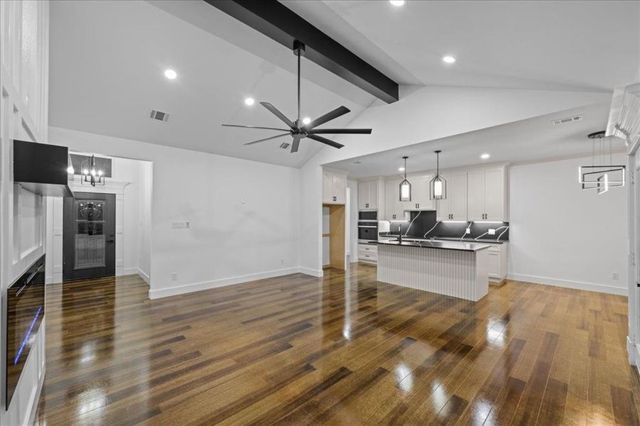 Kitchen with dark countertops, off-white cabinetry, kitchen island, wood-style flooring, open floor plan perfect for entertaining. Kitchen with dark countertops, off-white cabinetry, kitchen island, wood-style flooring, open floor plan perfect for entertaining.