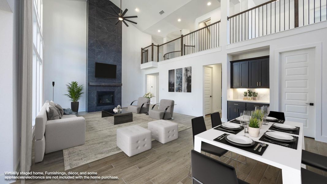 Living room featuring a high ceiling, light wood-style flooring, a tiled fireplace, a ceiling fan, and recessed lighting